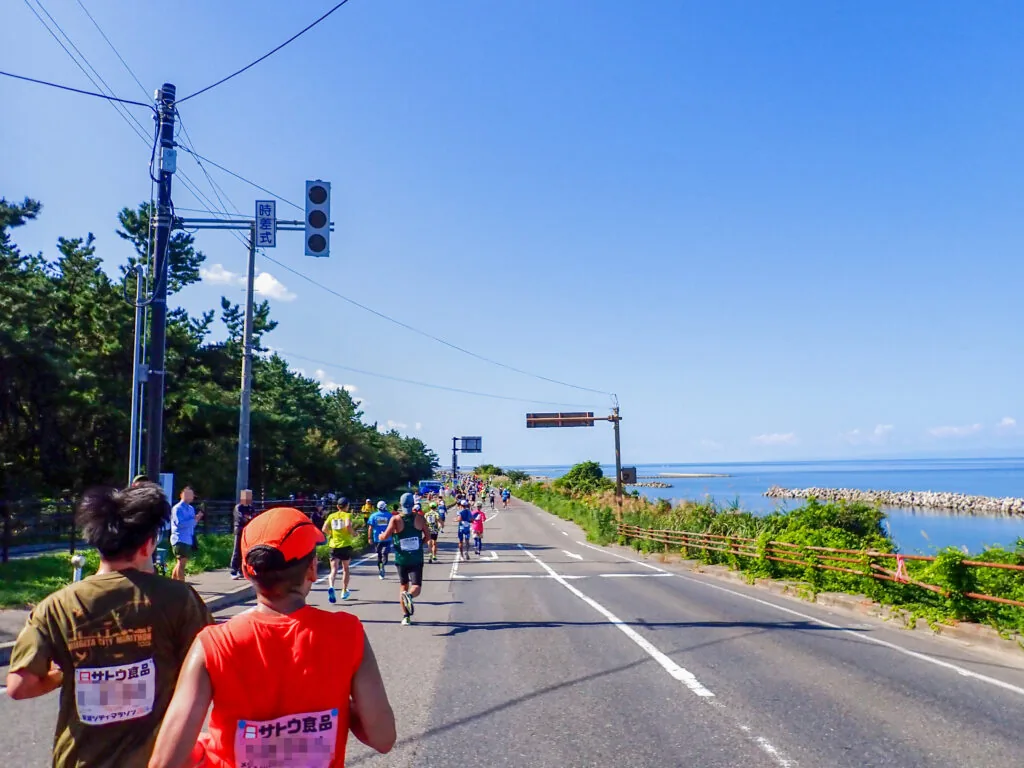 松林と日本海に挟まれた海岸道路を走るランナーたち