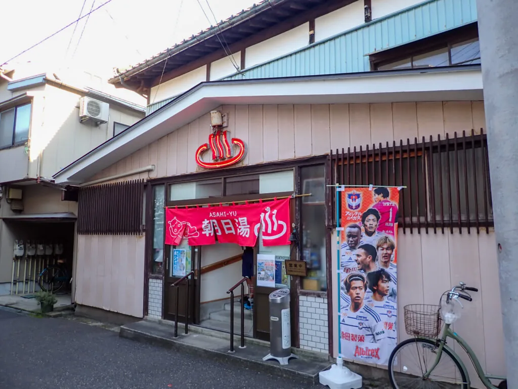 赤い暖簾に「朝日湯」と書かれた銭湯の入口