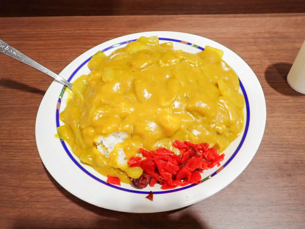 とろみのある黄色いルーに福神漬けを添えた、バスセンターのカレー