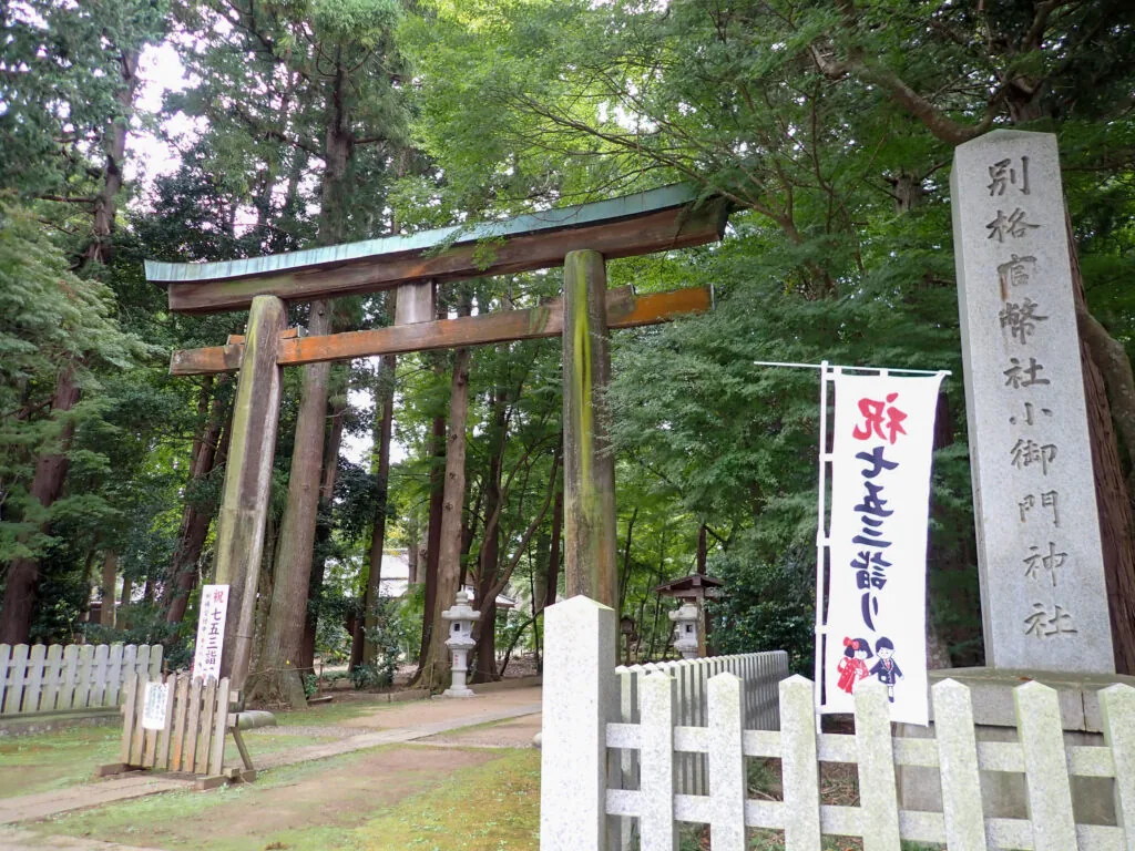 「別格官幣社 小御門神社」の社号標と、緑青の屋根が付いた木の鳥居