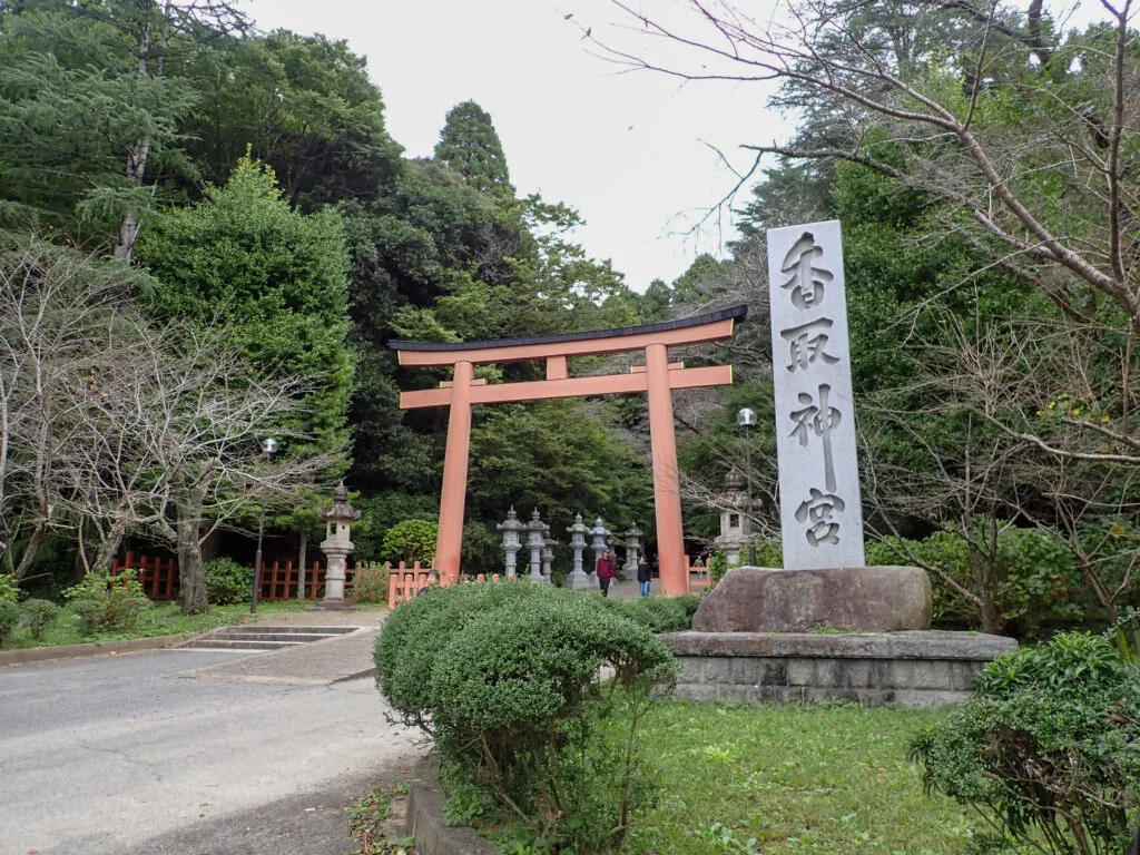 朱色の鳥居と「香取神宮」の社号標、奥に並ぶ石灯籠
