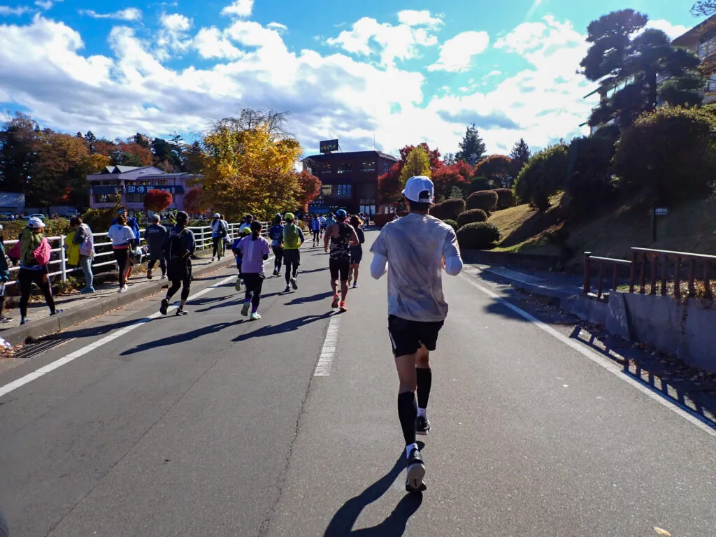 和風の建物と紅葉した木々が並ぶ道を、ゴールへ向かって走るランナーたち