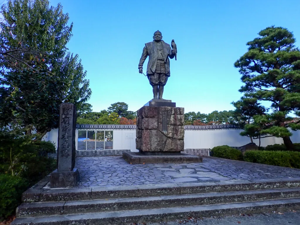石畳の広場にそびえる、鷹を手にした武将の銅像