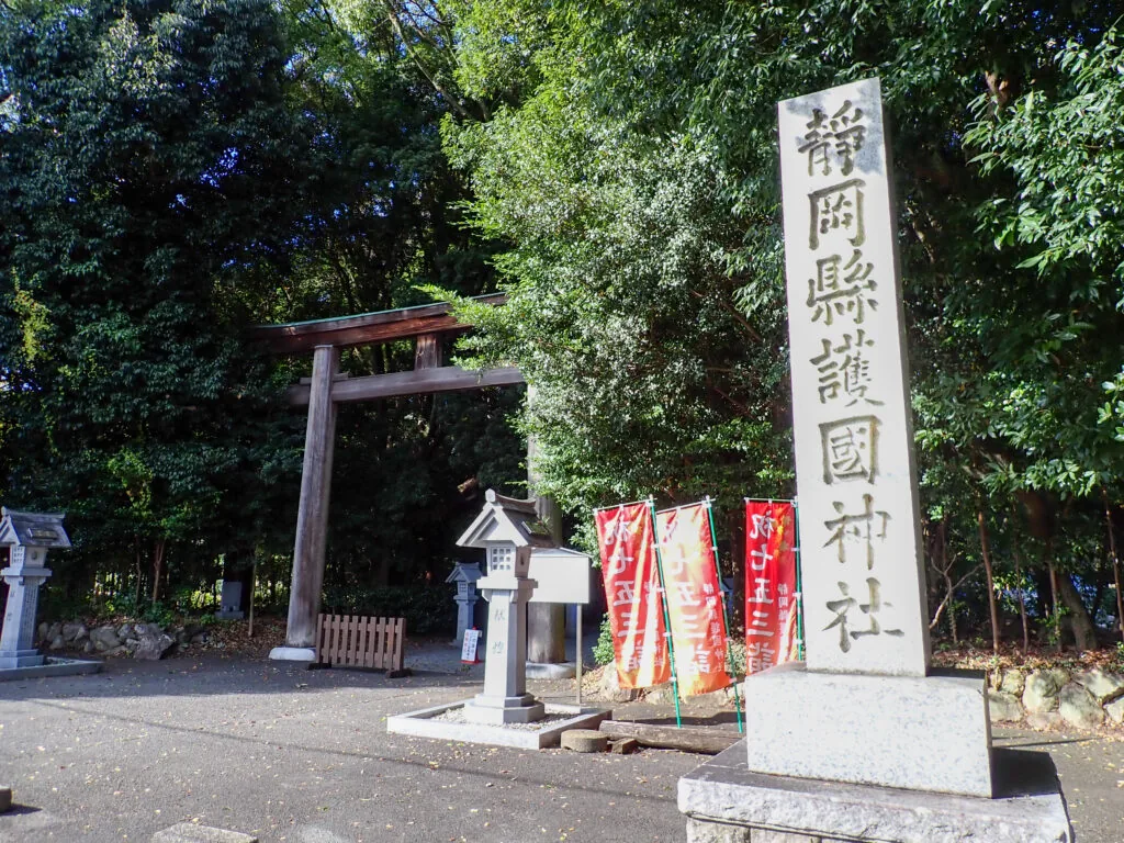 「静岡縣護國神社」と刻まれた社号標と、奥に見える木の鳥居
