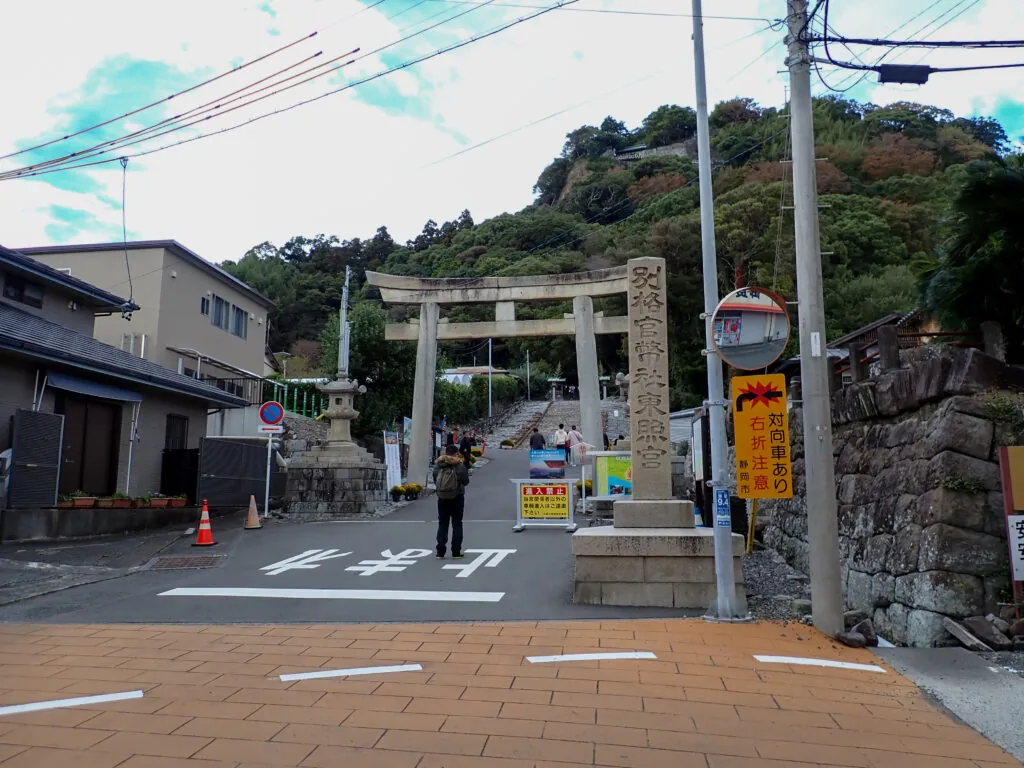 「久能山東照宮」の社号標と石の鳥居。鳥居の先に石段が山上へ続く