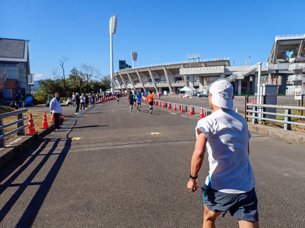 遠くにスタジアムが見える、ゴール手前の広い道を進むランナーたち