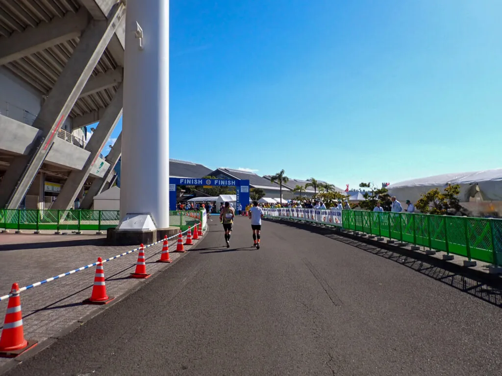 スタジアムの脇を通り、遠くに「FINISH」のゲートが見える道を進むランナーたち