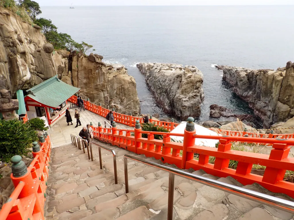 海に切り立つ岩々と、朱色の欄干が続く鵜戸神宮の石段