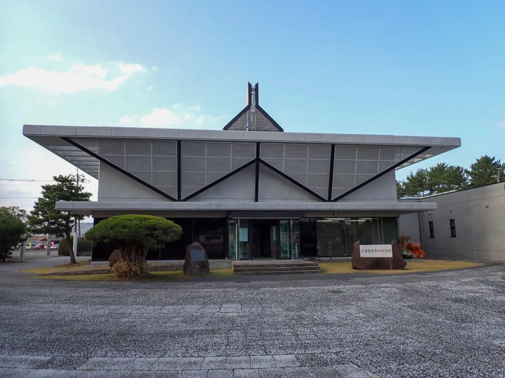 屋根が大きく張り出した万世特攻平和祈念館の建物と、石敷きの前庭