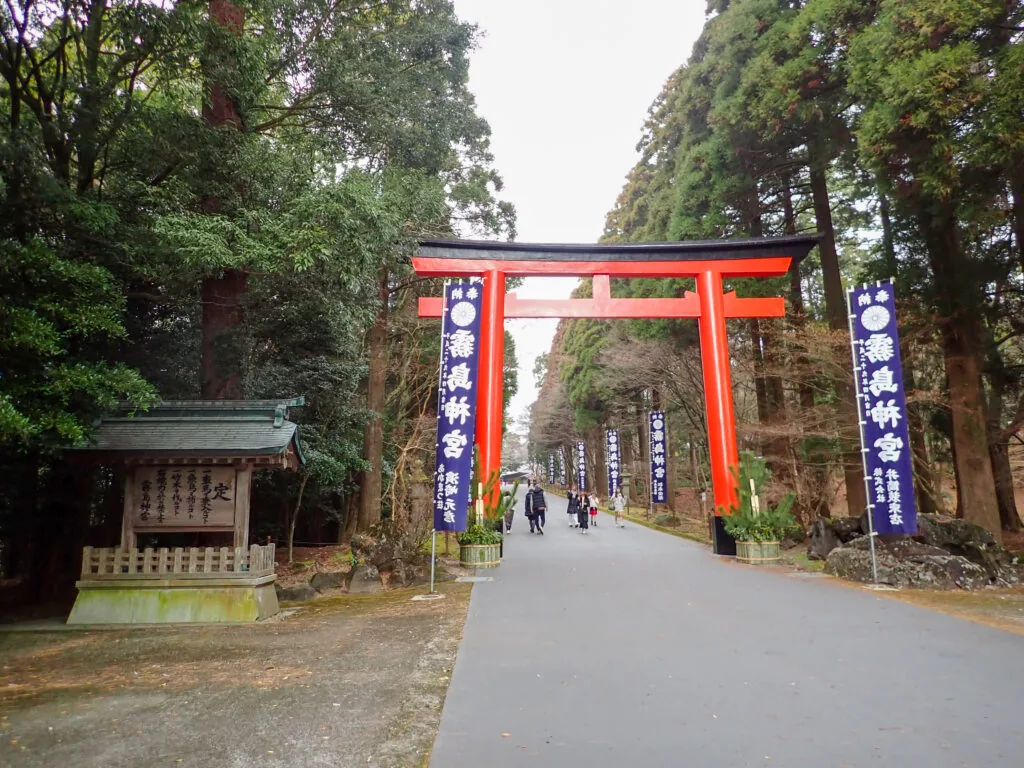 杉木立の中、「霧島神宮」の幟が並ぶ参道と朱色の大鳥居