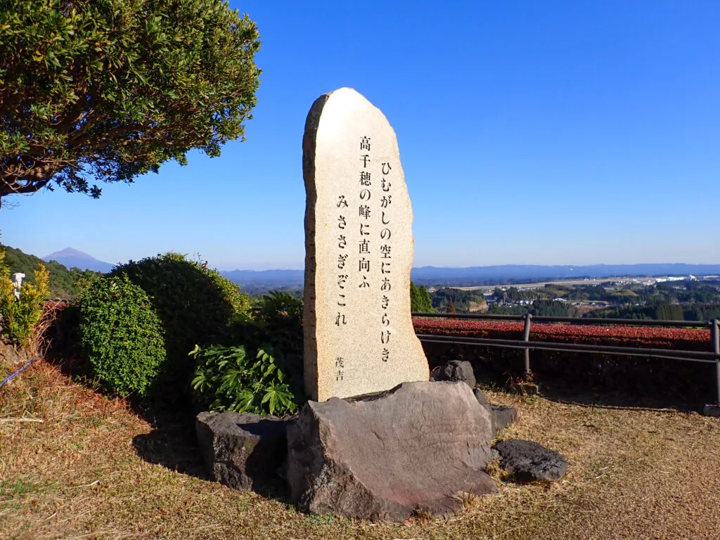 斎藤茂吉の歌が刻まれた自然石の歌碑と、遠くに見える山並み