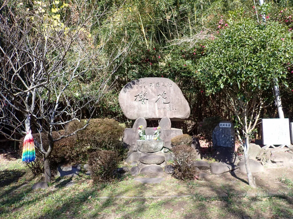 「桜花」と刻まれた大きな丸い自然石の碑と、周囲の木々