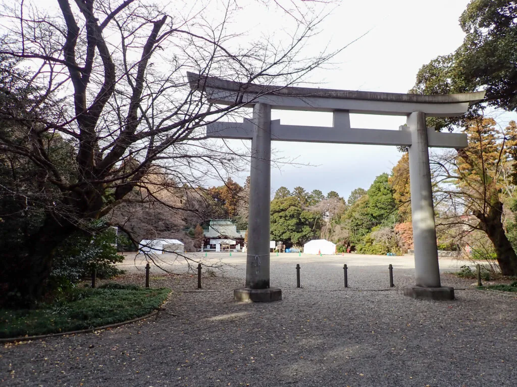 広い砂利の境内に立つ石の鳥居と、奥に見える社殿