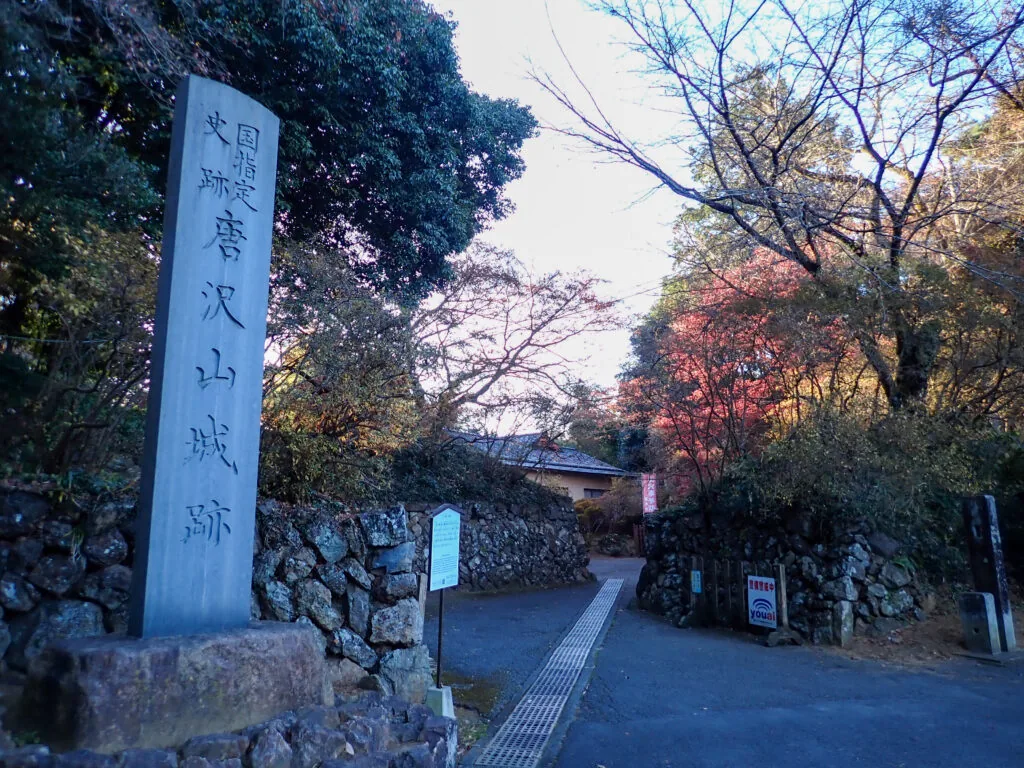 「唐沢山城跡」の石碑と、石垣に沿って続く道