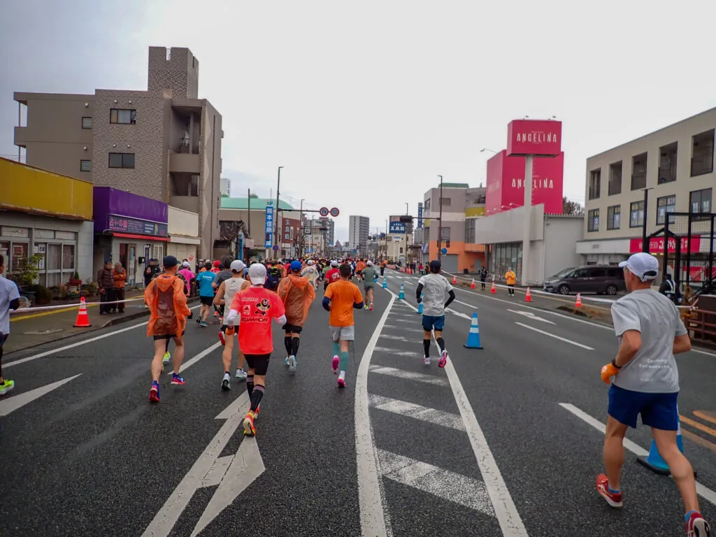 商店が並ぶ通りを進むランナーたち