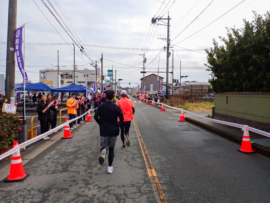 給水所のテントが並ぶ沿道を進むランナーたち