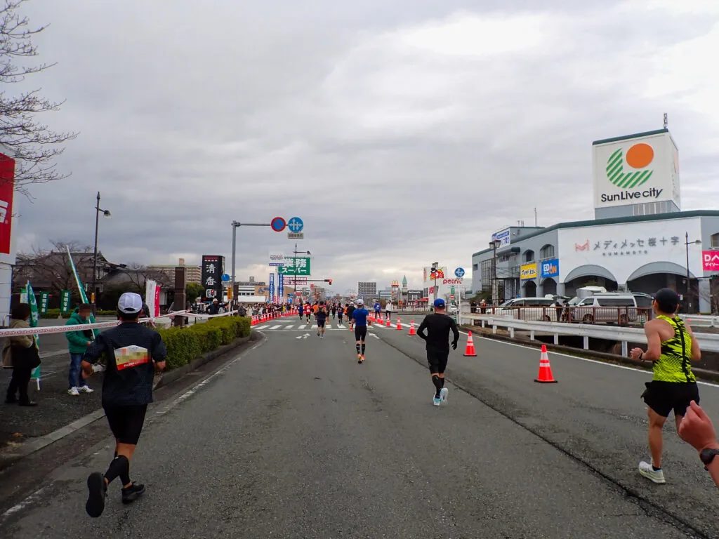 大型商業施設が見える広い通りを進むランナーたち