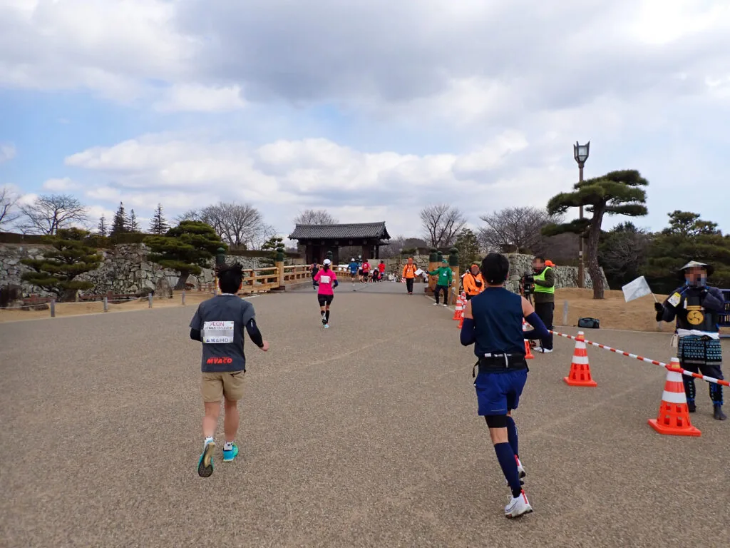姫路城の敷地内、門へ続く道を進むランナーたち