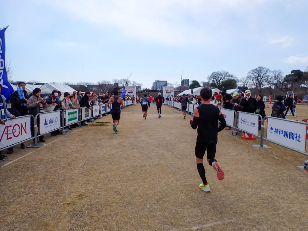 沿道の応援を受けてゴール前の直線を走るランナー