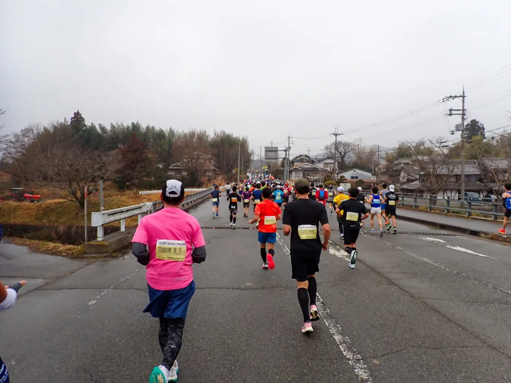 橋を渡って住宅地へ向かうランナーの列