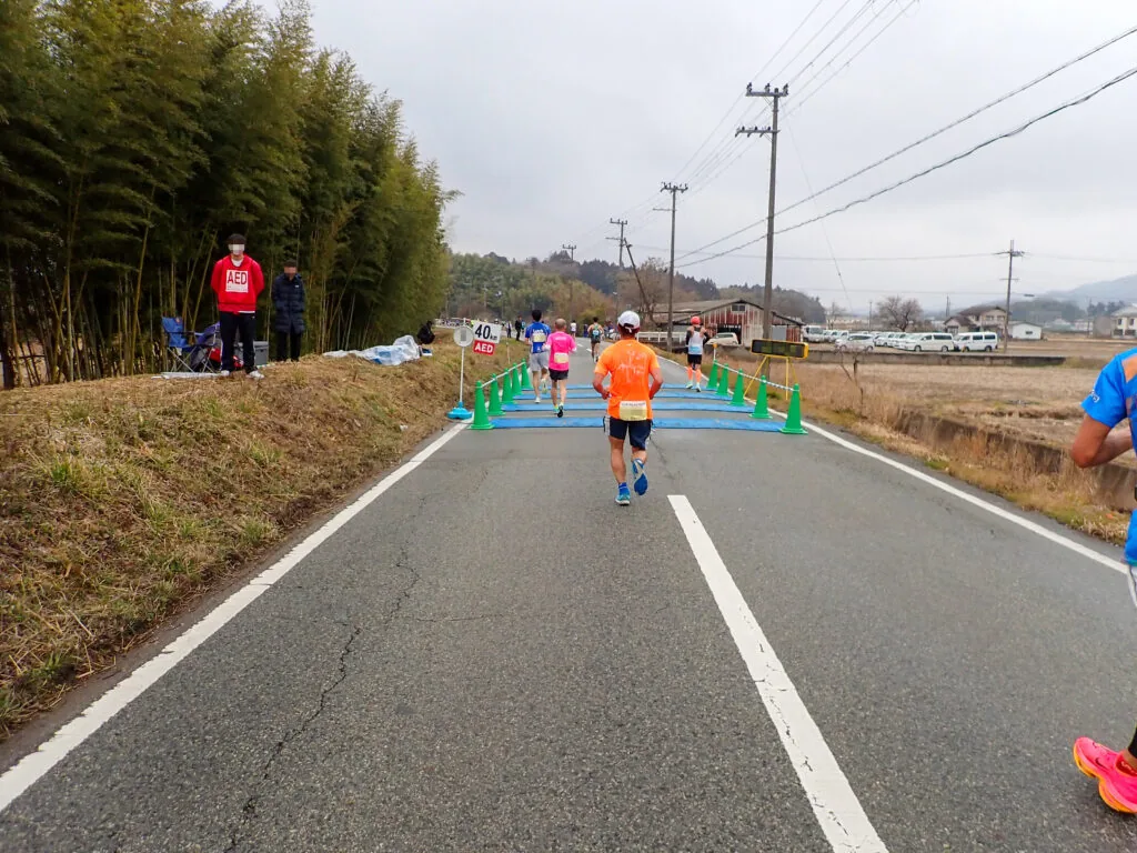 竹林の脇の道に敷かれた青いマットを通過するランナー