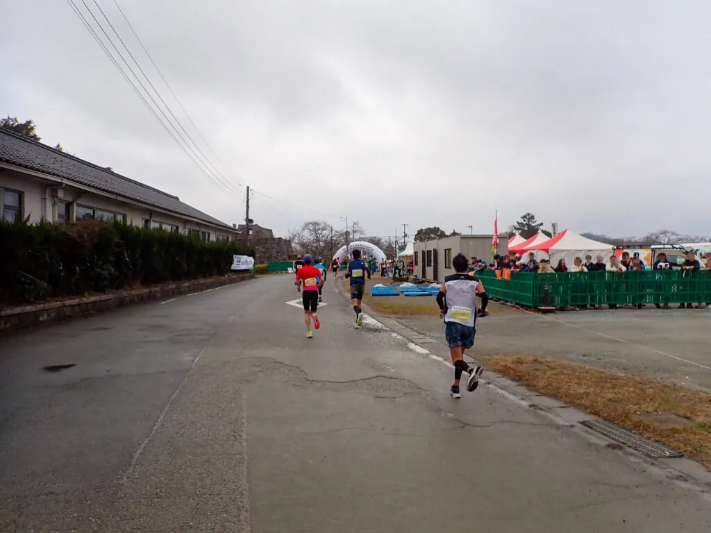 ゴール会場のテントが見えてきた道を進むランナーたち