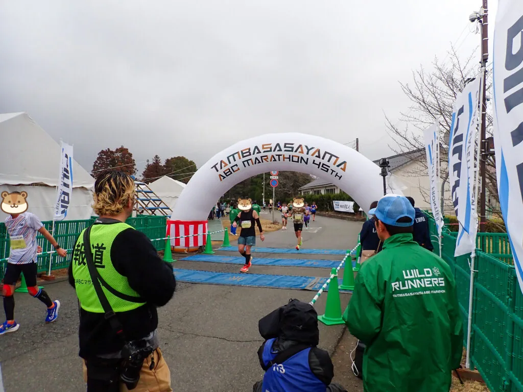 アーチ形のゴールゲートへ向かうランナーとスタッフ