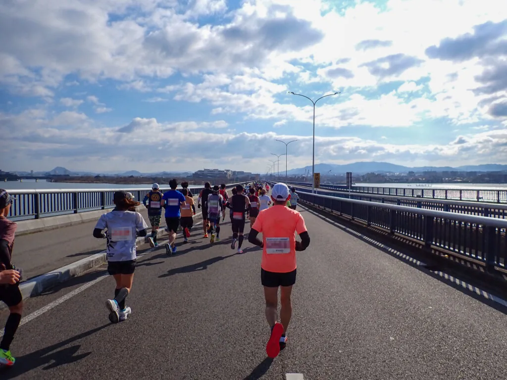 近江大橋の上から湖と山並みを望みながら走るランナーたち