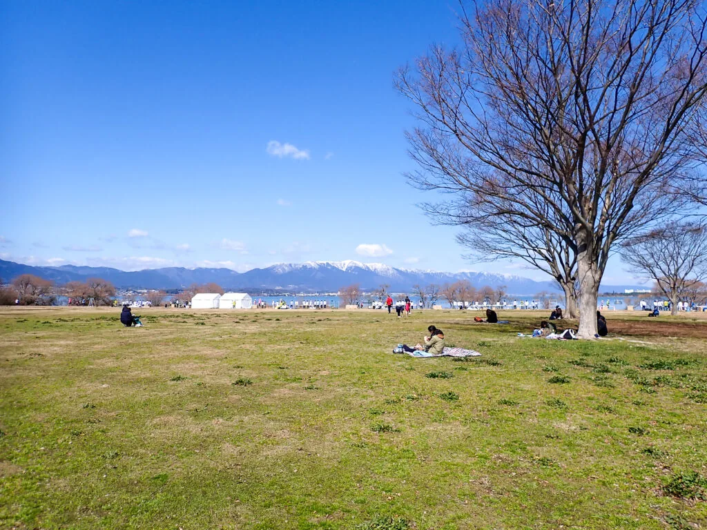 芝生広場から望む湖と雪をかぶった山並み