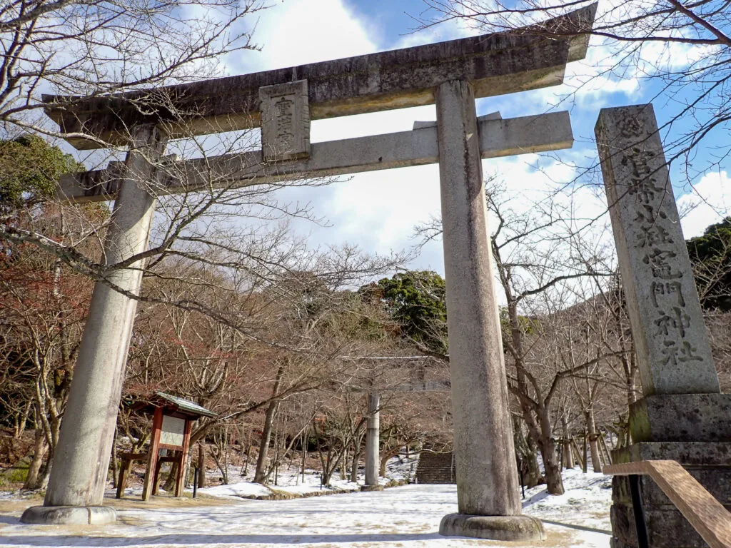 雪が残る境内に立つ石の鳥居と「官幣小社 竈門神社」の石柱