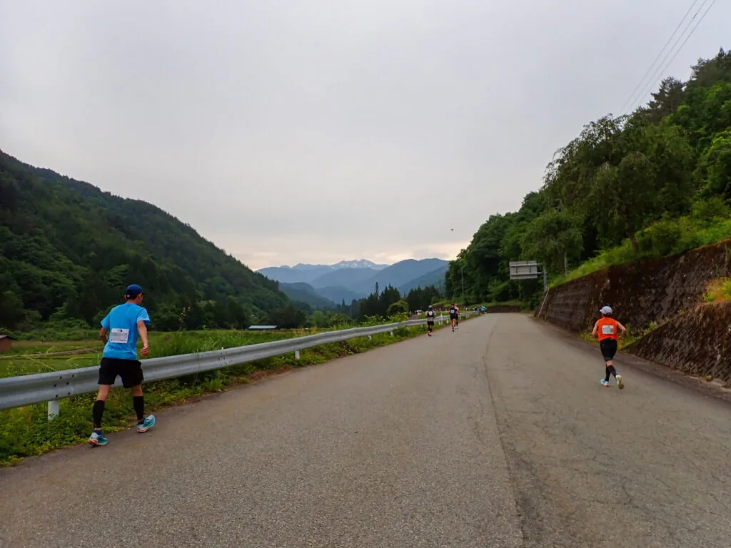 谷あいの広い道を進むランナー