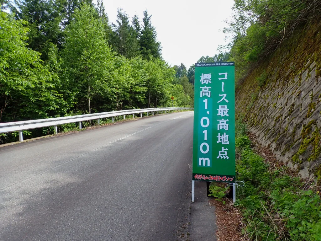 「コース最高地点 標高1,010m」と書かれた緑の看板