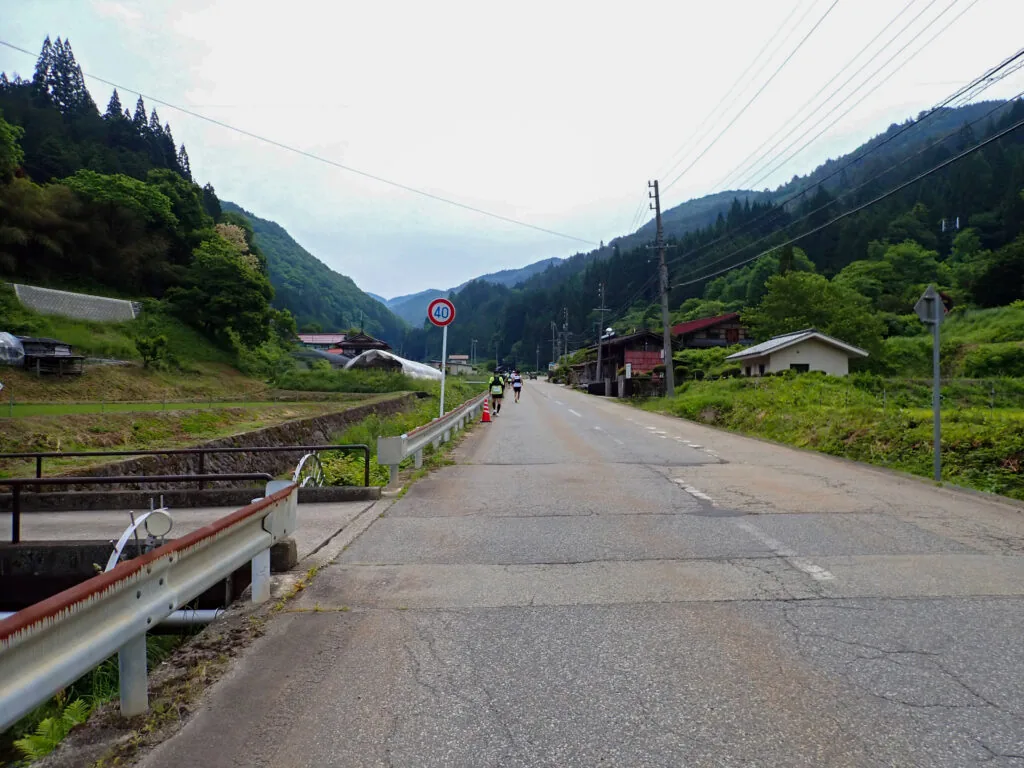 山に挟まれた集落の道を進むランナー