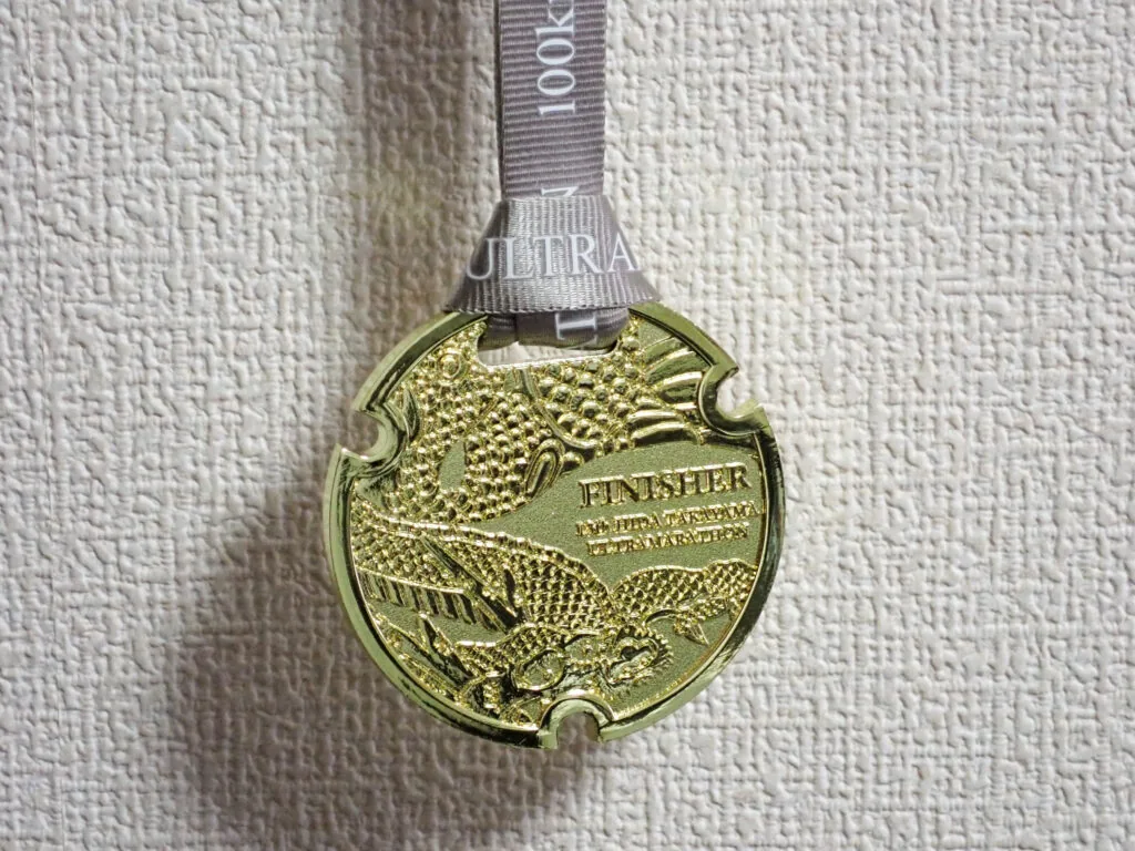「FINISHER」と刻まれた金色の100km完走メダル