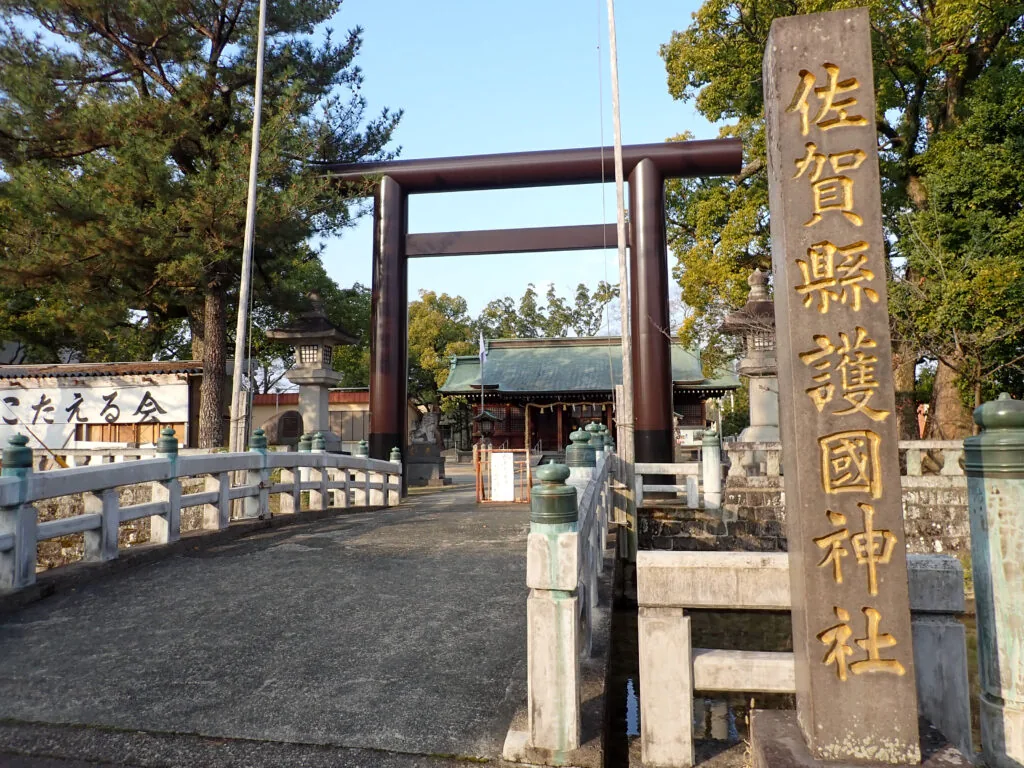 「佐賀縣護國神社」の石柱と、石橋の先に立つ鳥居