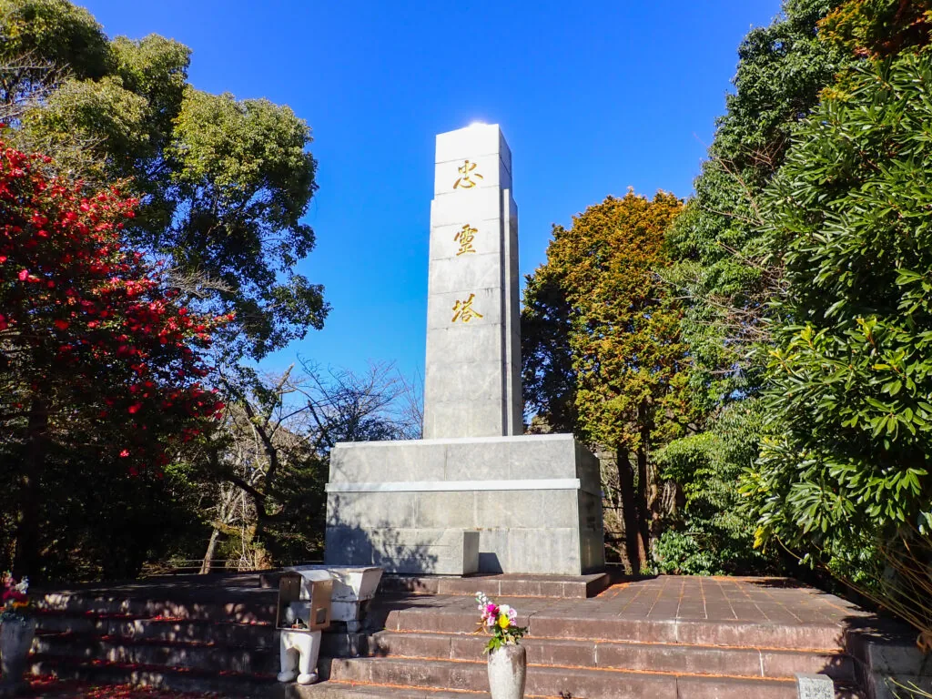 木々に囲まれた忠霊塔と手前に供えられた花