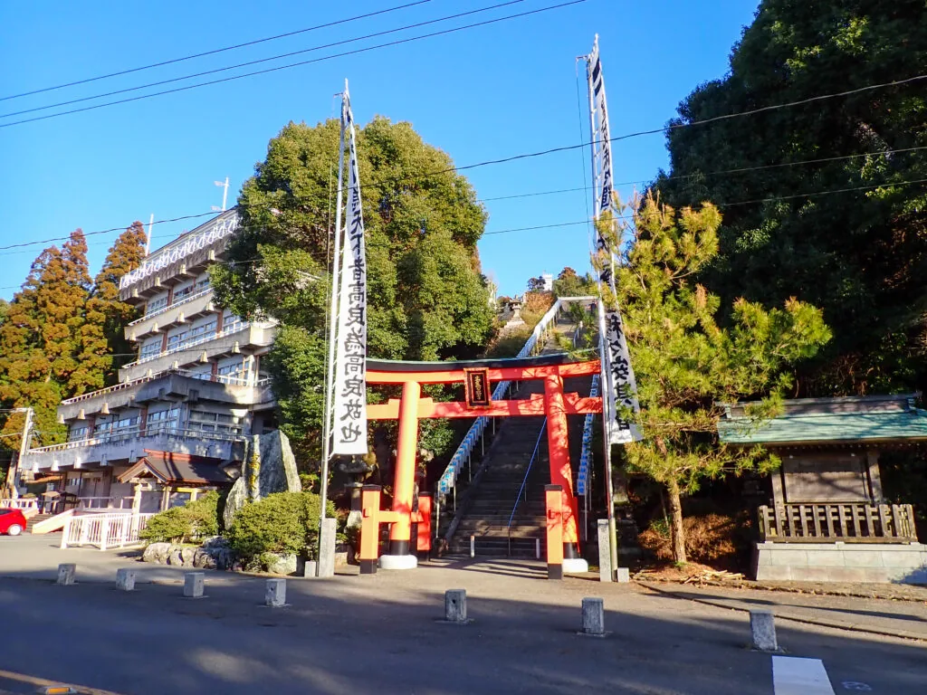 朱色の鳥居と石段、のぼり旗が立つ高良大社の入口