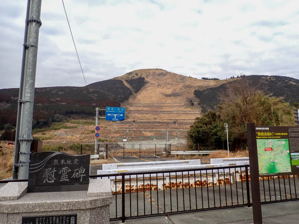 崩れた山肌を背にした熊本地震の慰霊碑と案内板