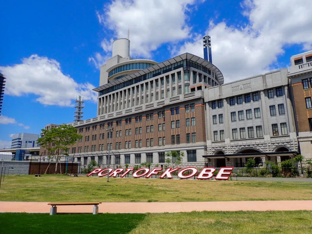 「PORT OF KOBE」の文字がある芝生の広場と港の建物