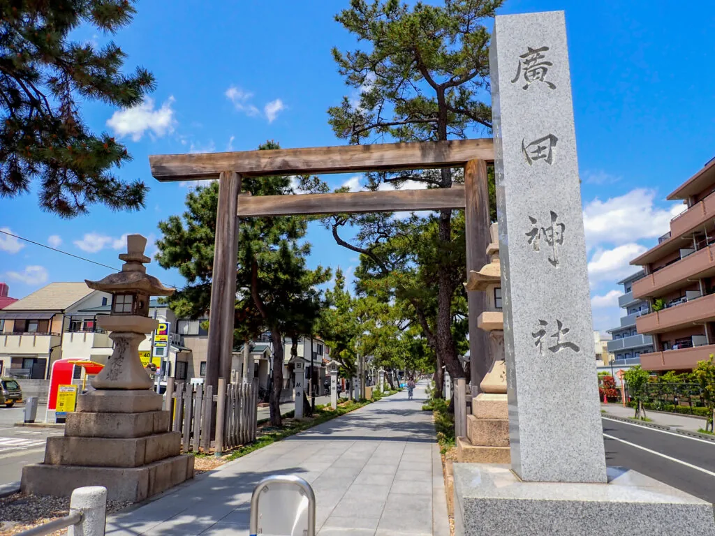 「廣田神社」の社号標と木の鳥居が並ぶ参道