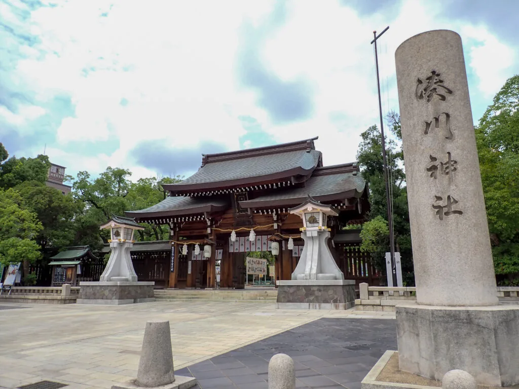 「湊川神社」の社号標と、奥に見える拝殿