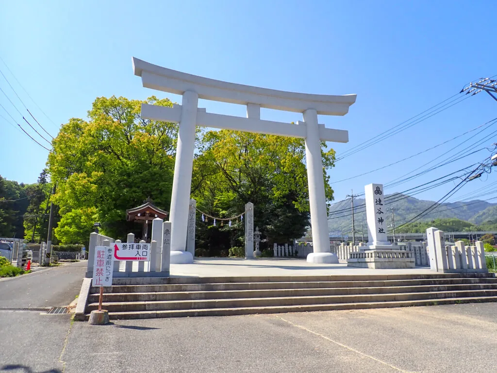 石段の上に立つ白い鳥居と社号標、速谷神社の入口