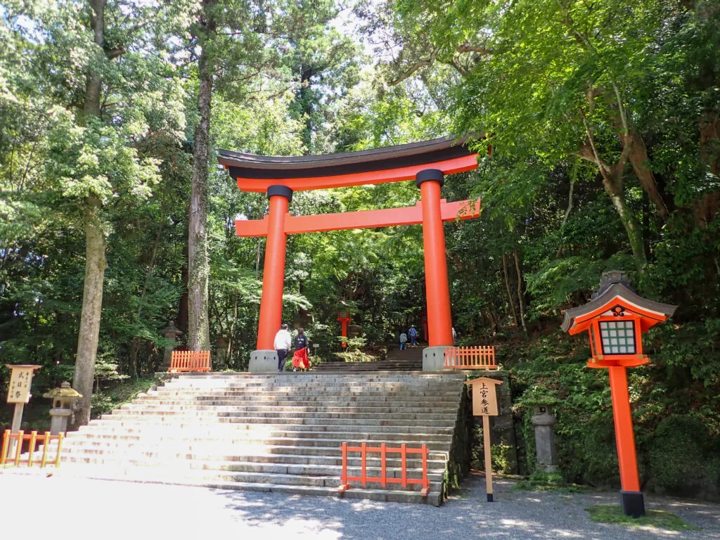 石段の上に立つ朱塗りの鳥居と赤い灯籠