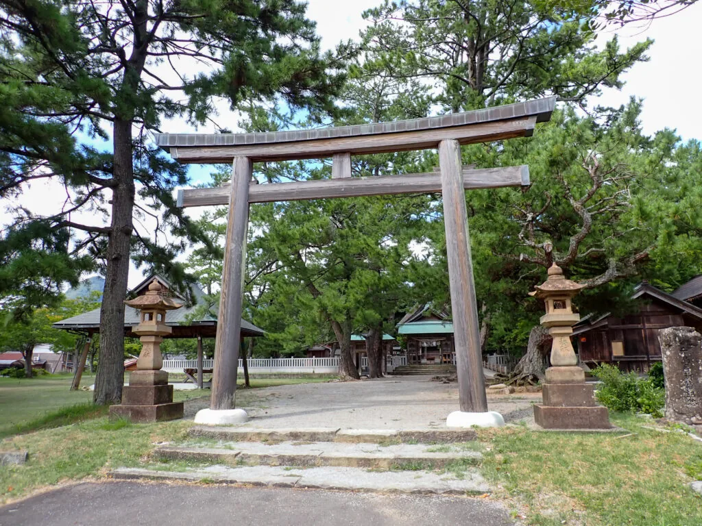 松に囲まれた水若酢神社の鳥居と石灯籠