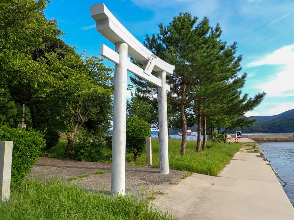 海沿いの岸壁近くに立つ黒木神社の白い鳥居
