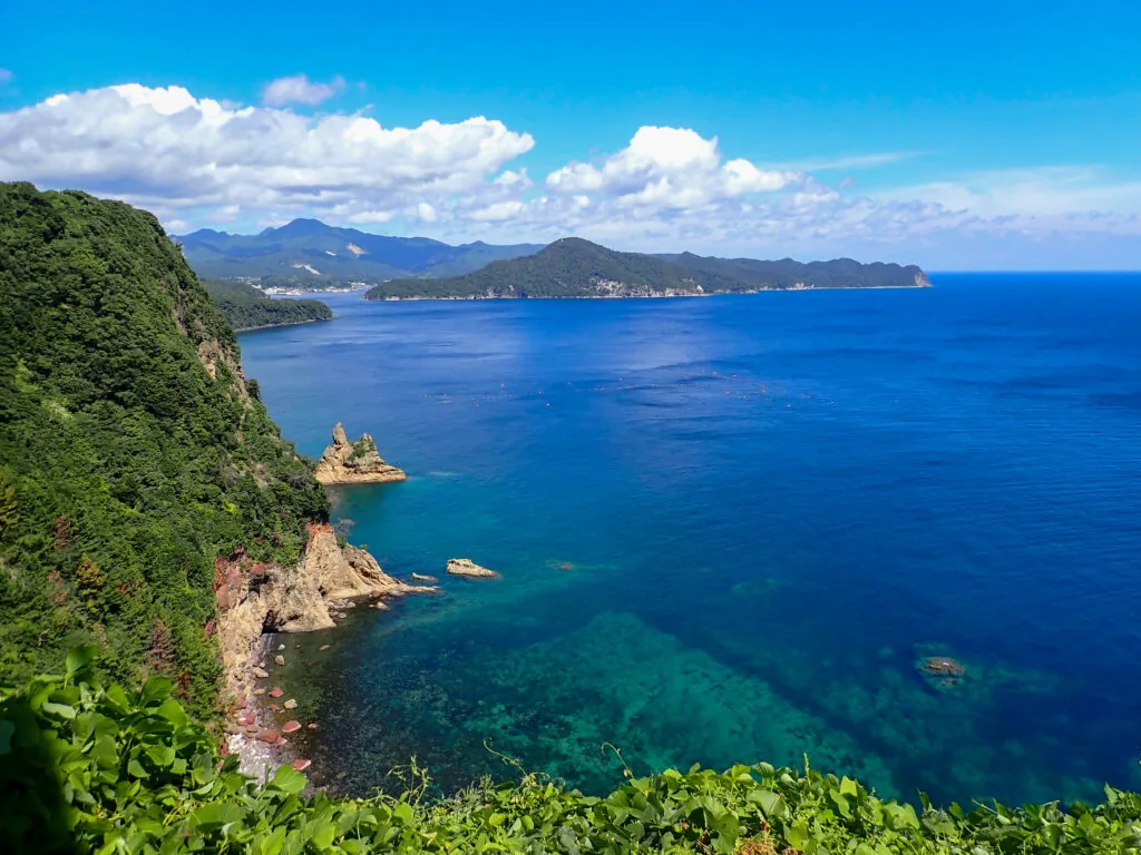 切り立つ緑の崖と透き通った青緑色の海