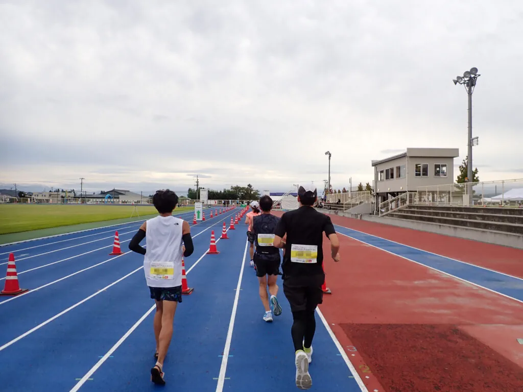競技場のトラックを走って2周目へ向かうランナーたち