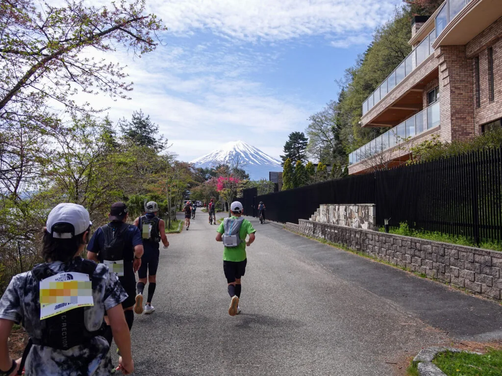 桜の枝の向こうに富士山が見える道を走るランナーたち
