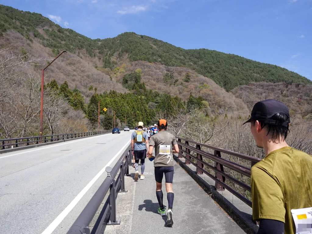 山あいの道路沿いの歩道を走るランナーたち
