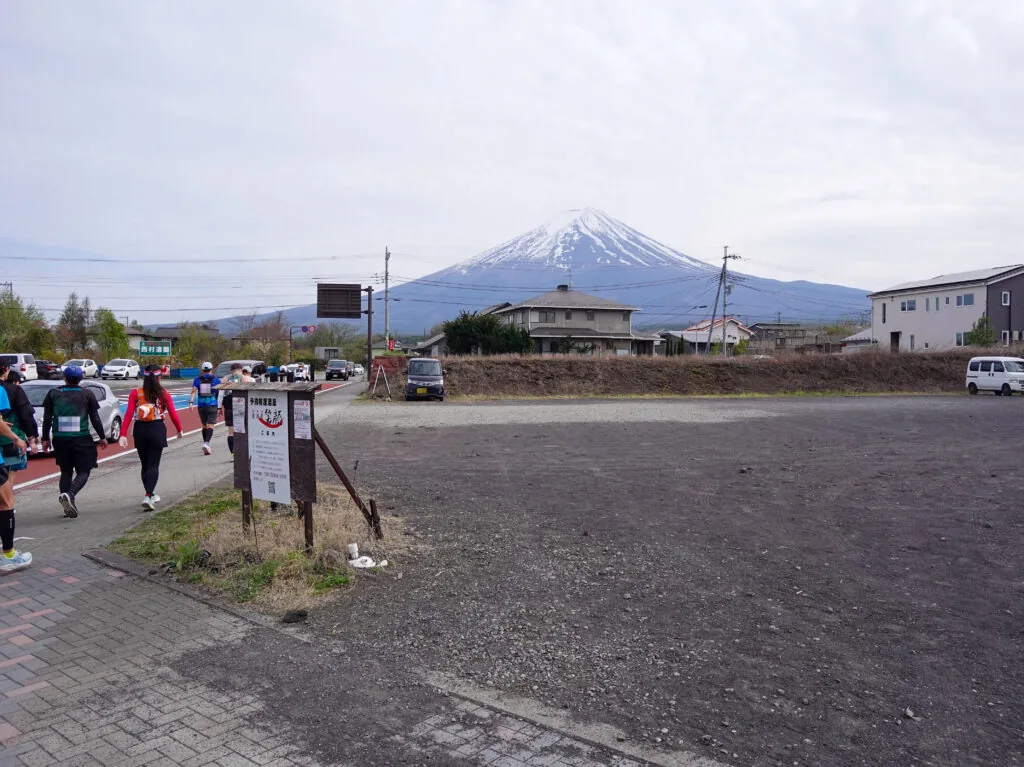 富士山を遠くに望む空き地の脇を進むランナーたち